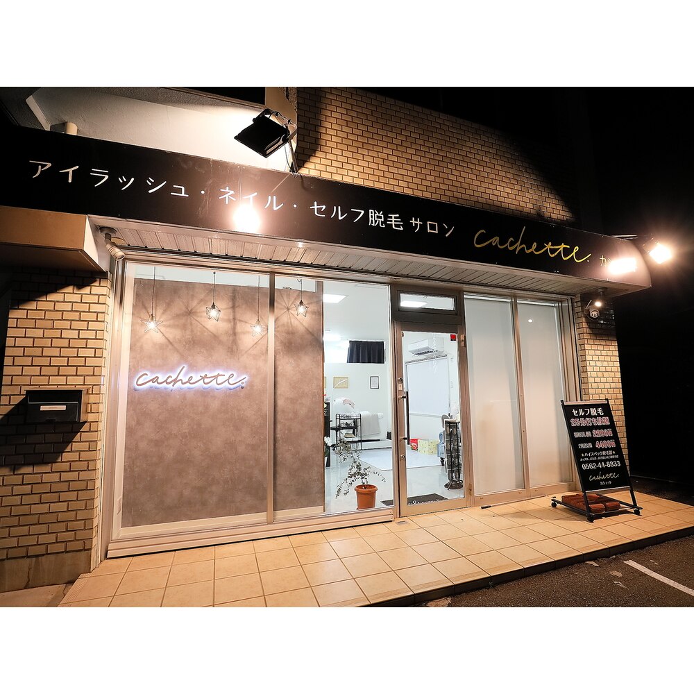 夜のcachette外観。窓にネオンのロゴが灯っている